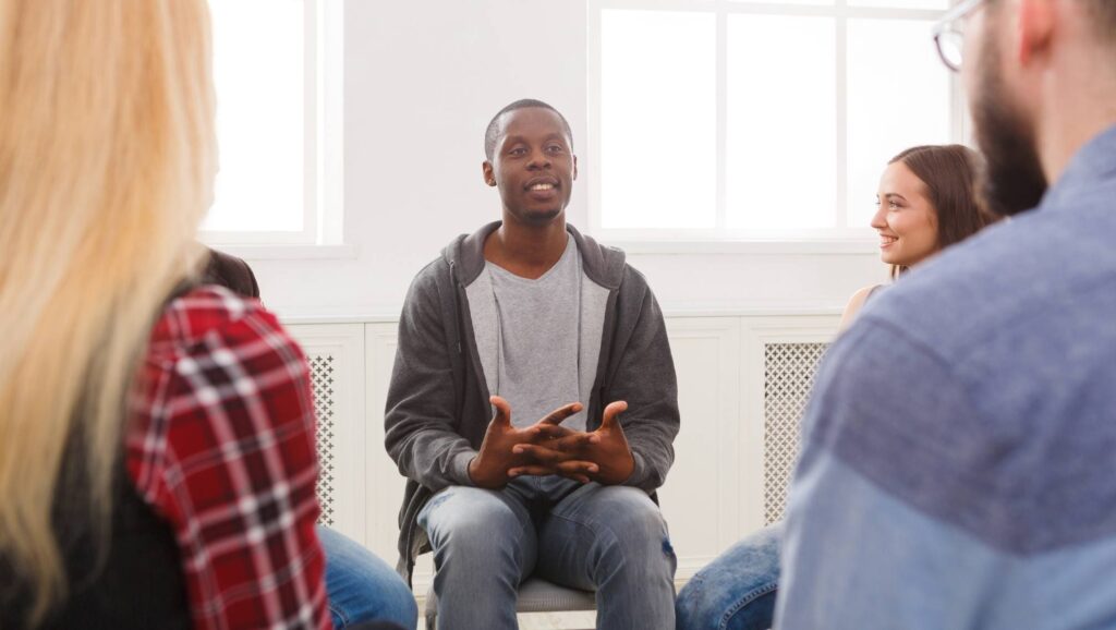 Man opening up in a group therapy session in Denver.